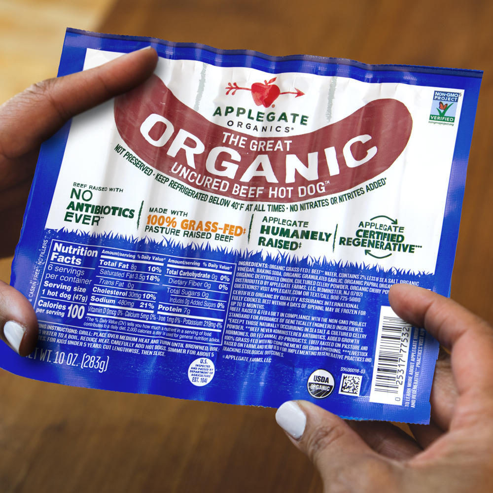 Hands holding an Applegate package of The Great Organic Uncured Beef Hot Dog.